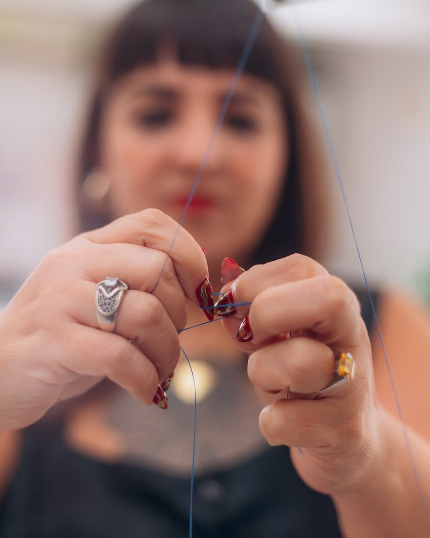 Mãos passando a linha, no acabamento da costura